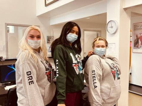 Three clinic staff in hoodies personalized with their names