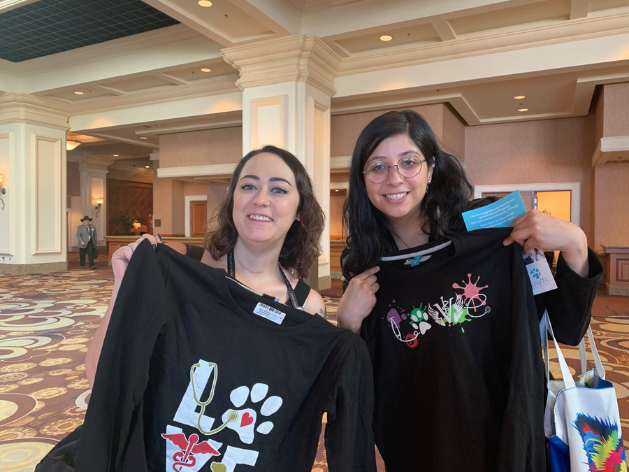 Two vet techs holding up new I Love Veterinary long sleeve shirts